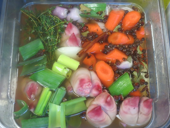Trotters in a marinade with white wine, veggies and spices