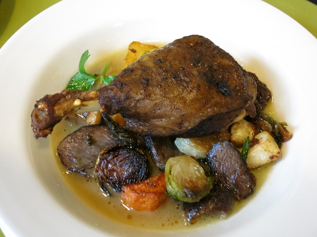 Crispy duck confit leg served on a warm salad of root vegetables, brussel sprouts, duck gizzards and parsley, with a sherry-duck jus.