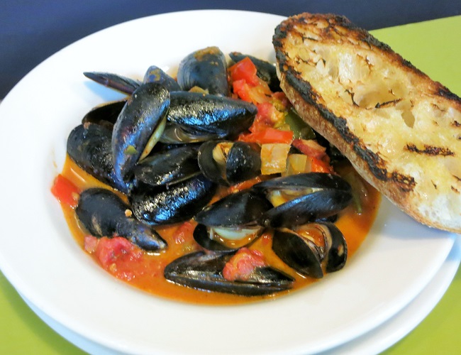 Penn cove mussels simmered with white wine and basque-style sweet pepper ragout with panchette, tomatoes, garlic, onion and pimente d'Espelette, served with grilled baguette.