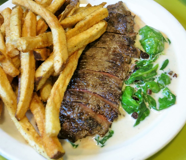 Petit grass fed beef strip steak steak, with brandied current cream sauce, wilted spinach and pommes frites.